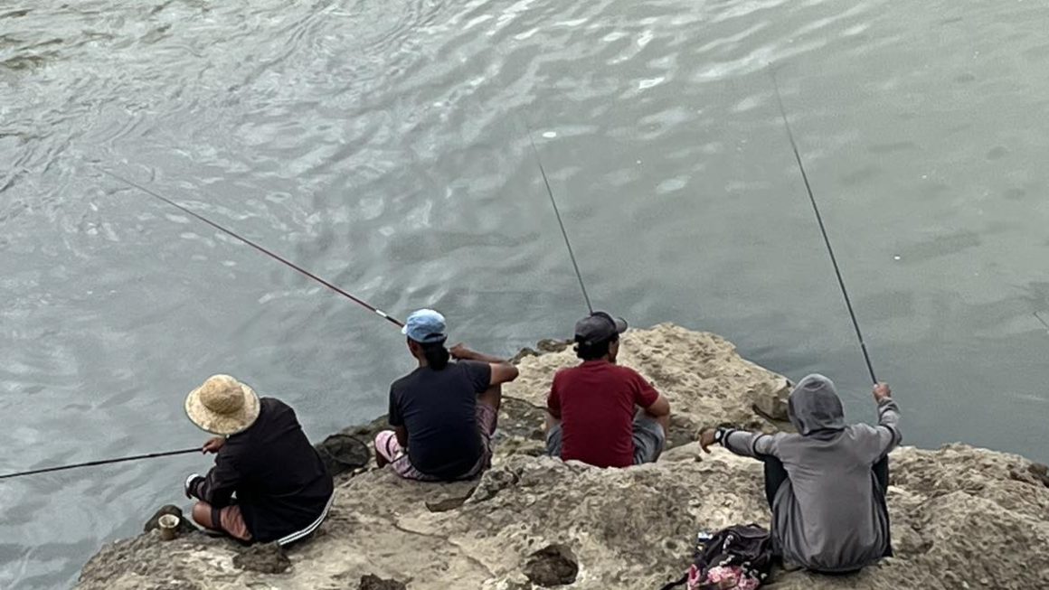 Line fishing along Pulangi River, under an unfinished bridge